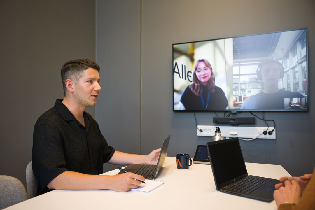 a person sitting at a table with laptops and a laptop on it