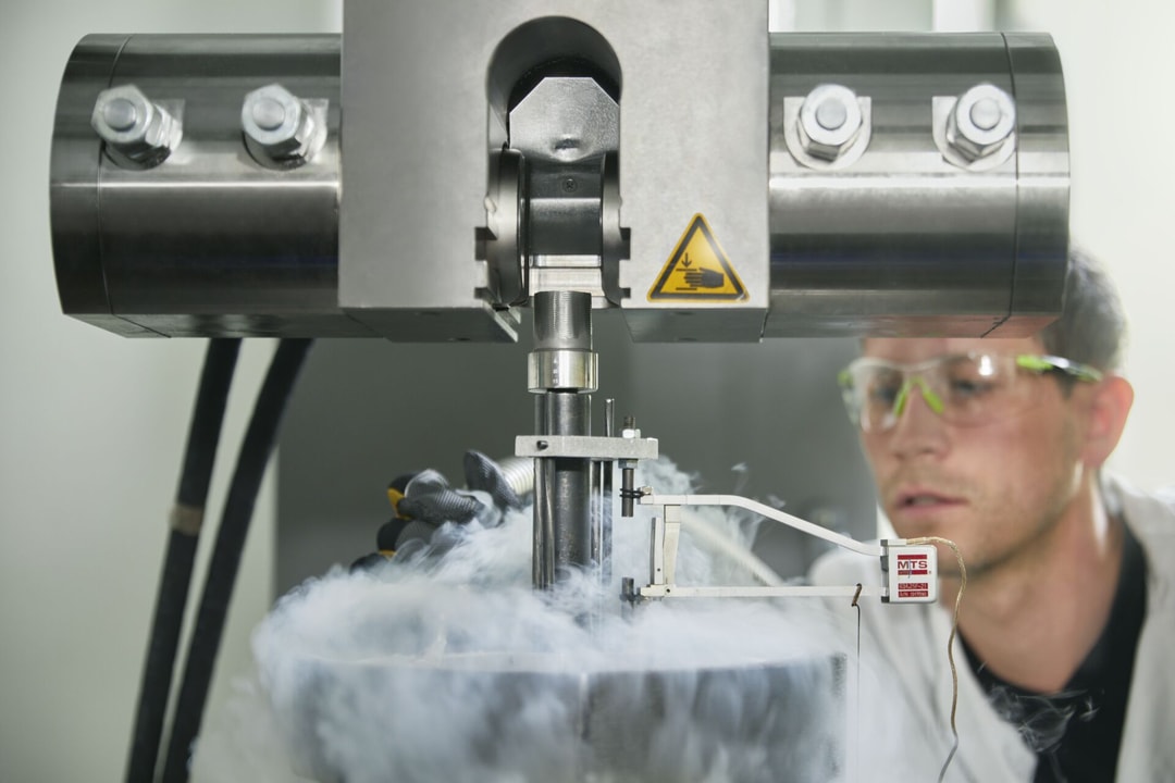 a person in a white coat and goggles working in a factory